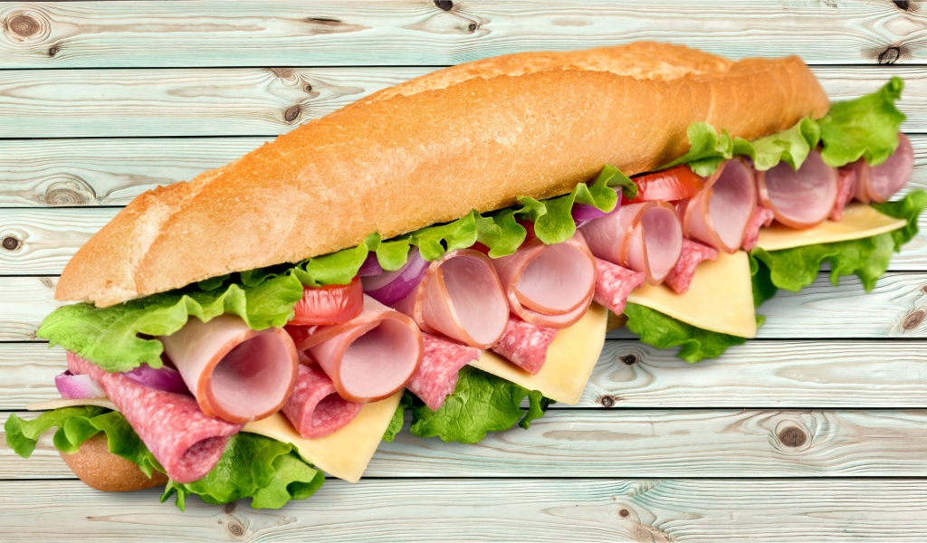 Большой бутерброд с колбасой, сыром и листьями салата