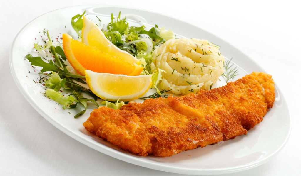 Картофельное пюре с мясом, кусочками апельсина и салатом на тарелке