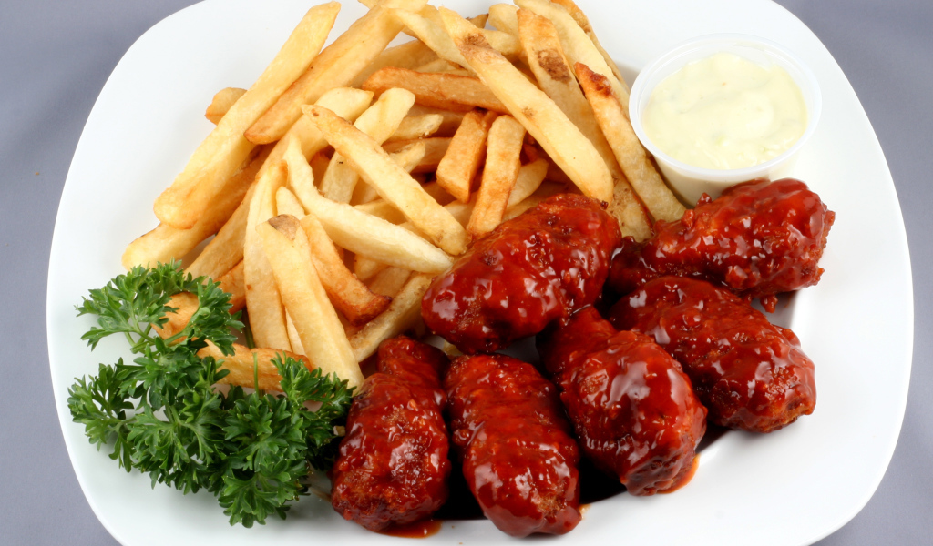 Тефтели в соусе с картофелем фри и петрушкой на тарелке