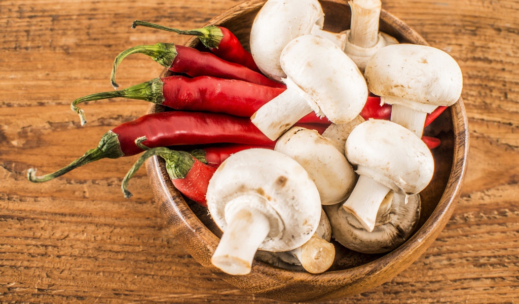 Грибы шампиньоны в деревянной миске с красным перцем