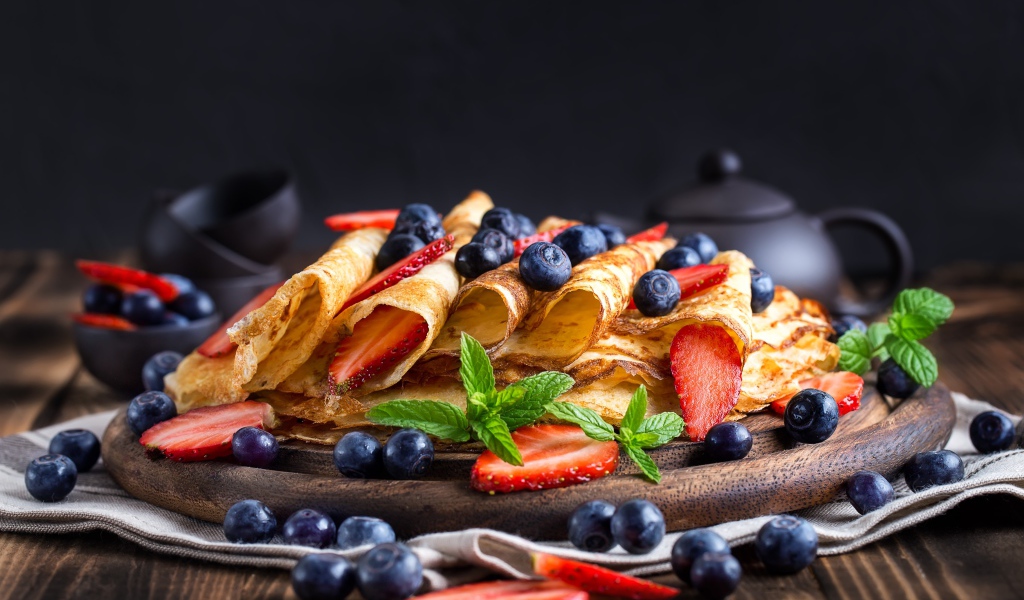 Блинчики с ягодами черники и клубники на столе