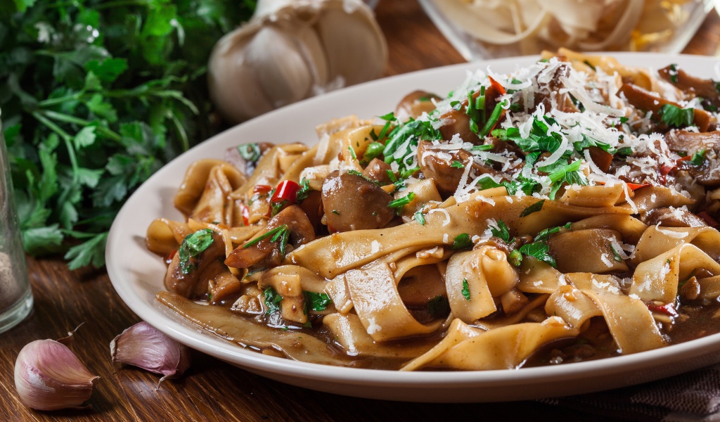 Паста с грибами, сыром и  зеленью на столе с чесноком 