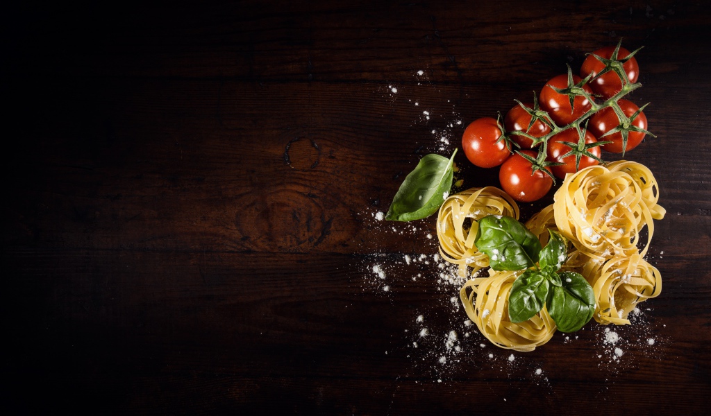 Паста с помидорами и листьями базилика на столе