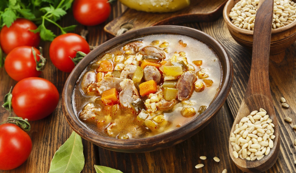 Перловый суп с сердечками на столе с помидорами 