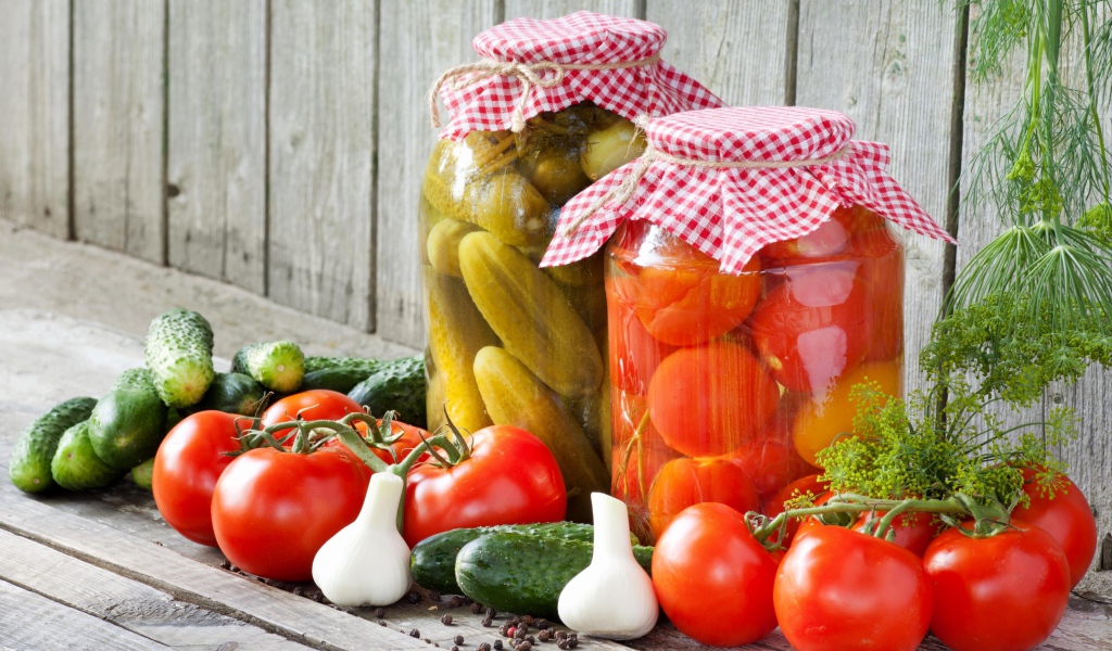 Соленья из огурцов и помидоров с овощами на столе