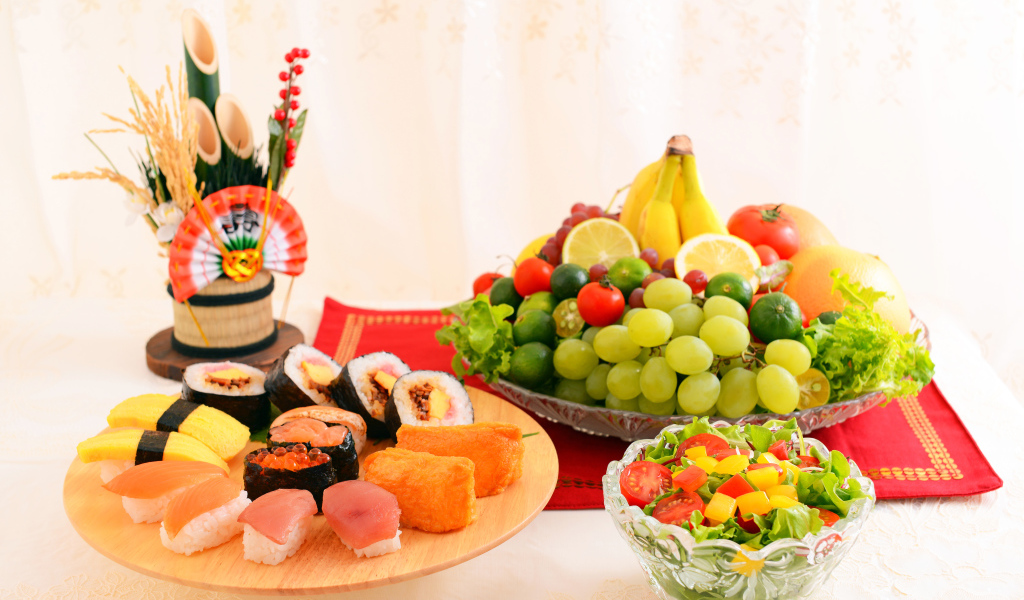 Роллы на столе с овощным салатом и фруктами 