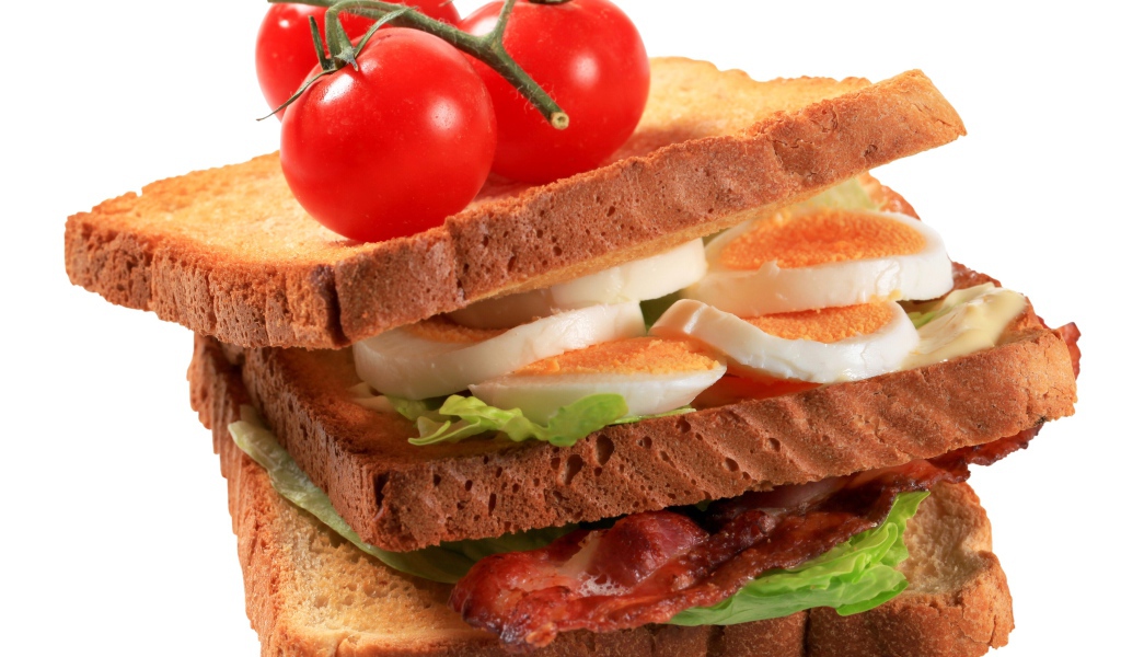 Сэндвич с яйцами, беконом и помидорами на белом фоне