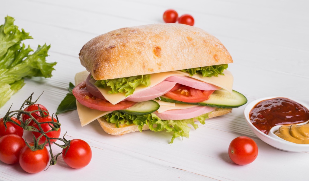 Сендвич с соусом и помидорами на столе 