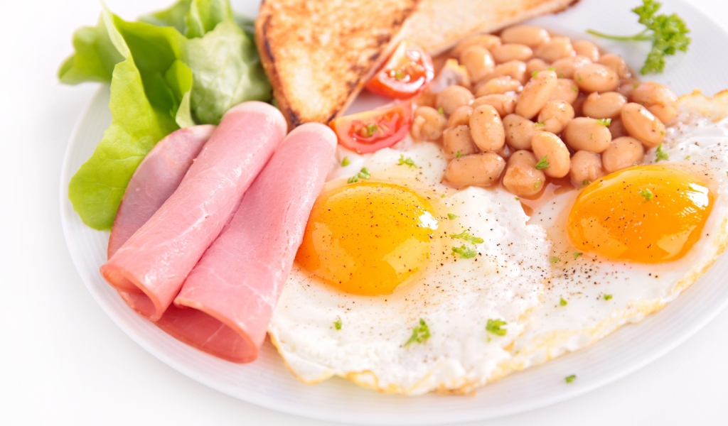Яичница с беконом, гренками, фасолью и листьями салата на завтрак