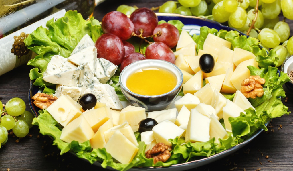 Нарезанный сыр на тарелке в виноградом 