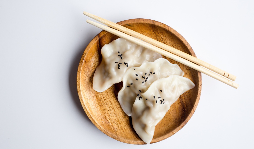 Три вареника на деревянной тарелке с палочками