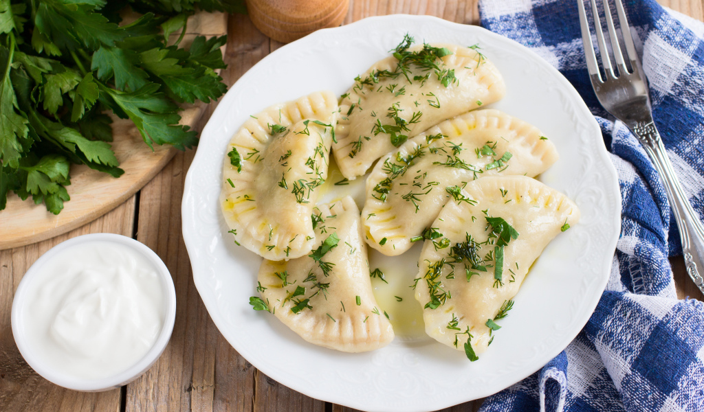Вареники с зеленью на белой тарелке 