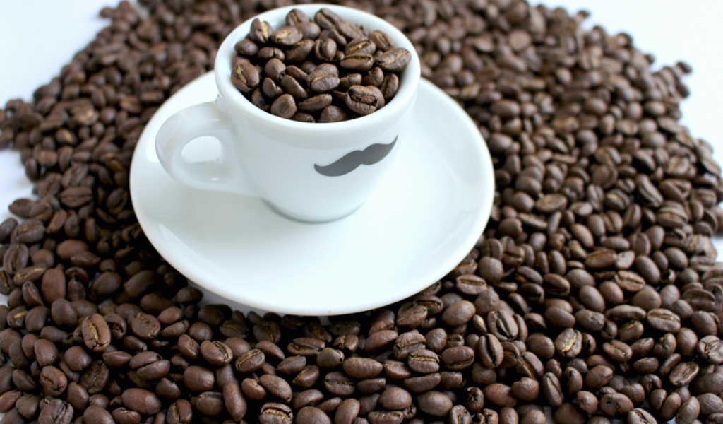 Белая чашка с жареными кофейными зернами стоит на столе с кофейными зернами