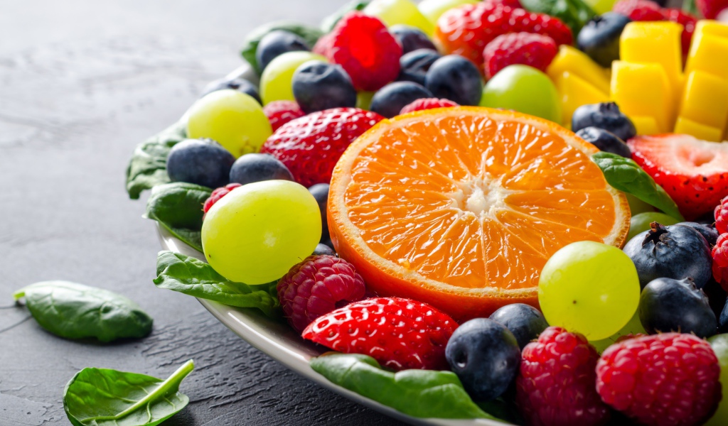 Аппетитные ягоды на тарелке с зелеными листьями базилика