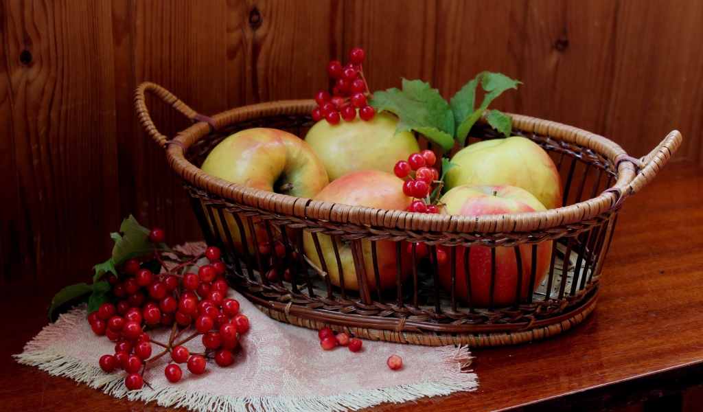 Красивые яблоки в корзине на столе с ягодами калины