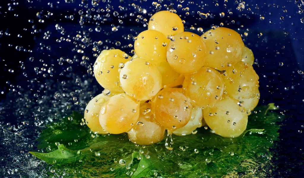 Гроздь белого винограда в брызгах воды