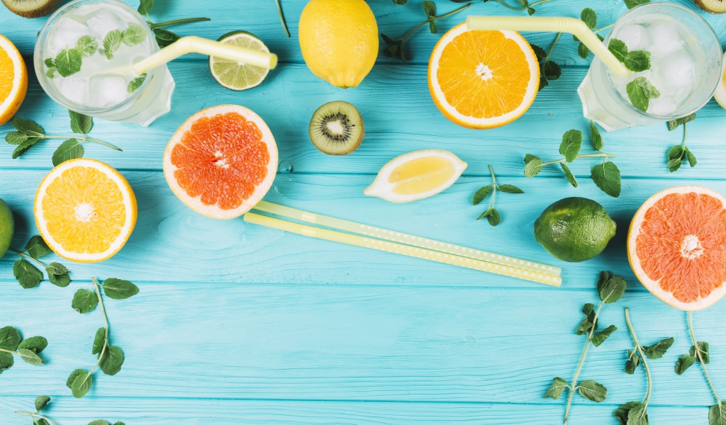 Цитрусовые фрукты на голубом столе с мятой и лимонадом