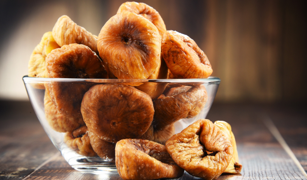 Инжир в стеклянной вазе на столе 