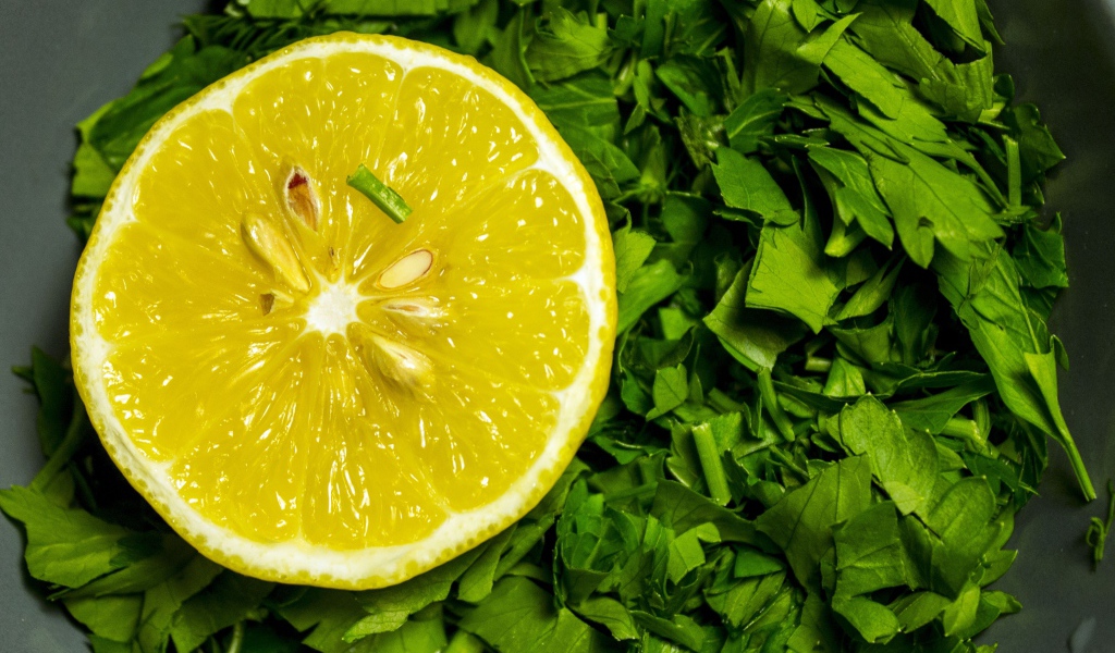 Половина желтого лимона с нарезанной зеленью петрушки 