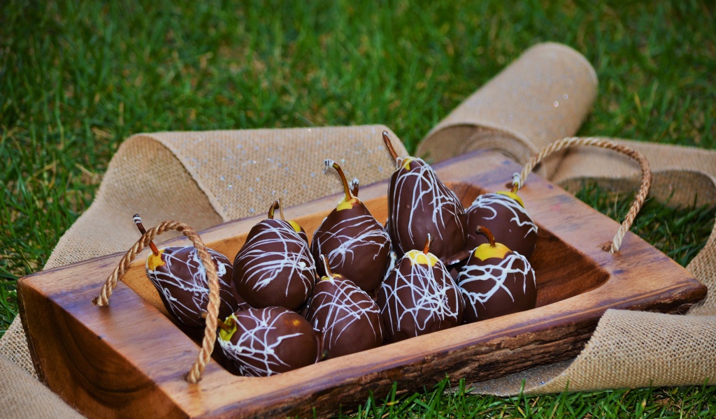 Груши в шоколадной глазури стоят на зеленой траве