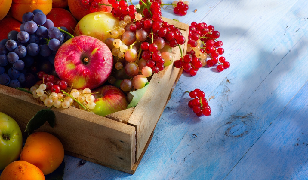 Спелые сочные ягоды и фрукты на столе в деревянном ящике