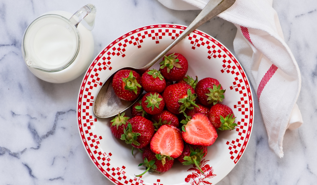 Спелая красная клубника с молоком на столе 