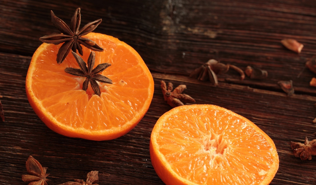 Две половины апельсина на деревянном столе с бадьяном