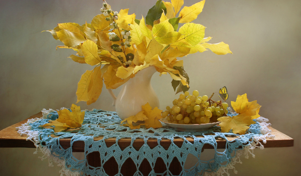 Белый виноград на столе с желтыми осенними листьями