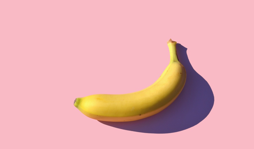 Желтый банан на розовом фоне