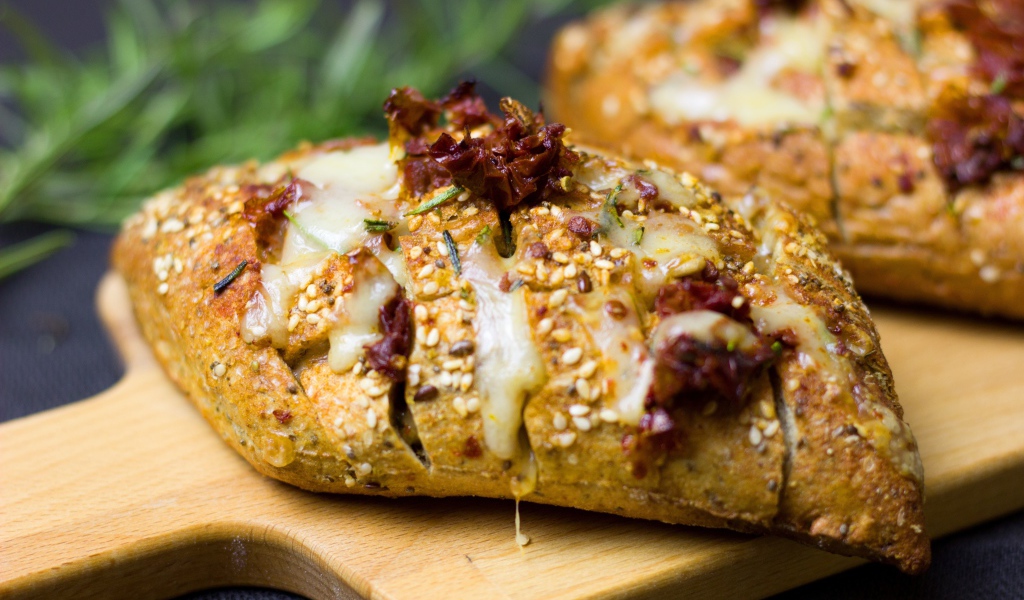 Булочка с кунжутом и сыром на разделочной доске 