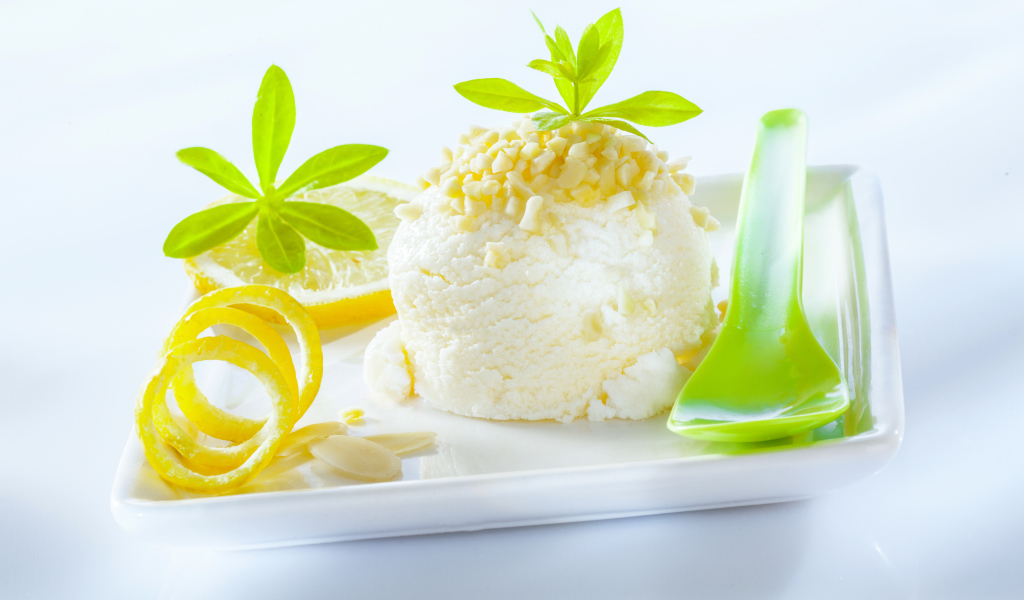 Шарик лимонного мороженого с фисташками с зеленой ложкой