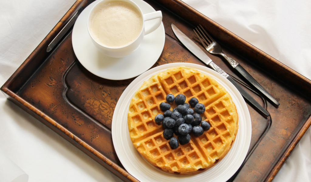 Чашка кофе и сладкие вафли с черникой на завтрак
