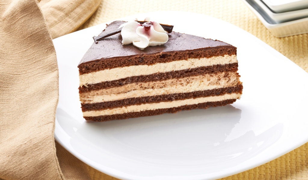 Большой кусок торта с кремом украшен цветком