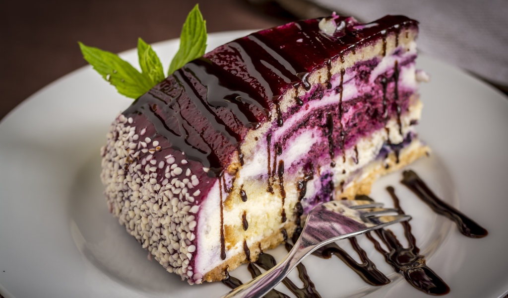 Кусок черничного пирога с джемом на белой тарелке с вилкой