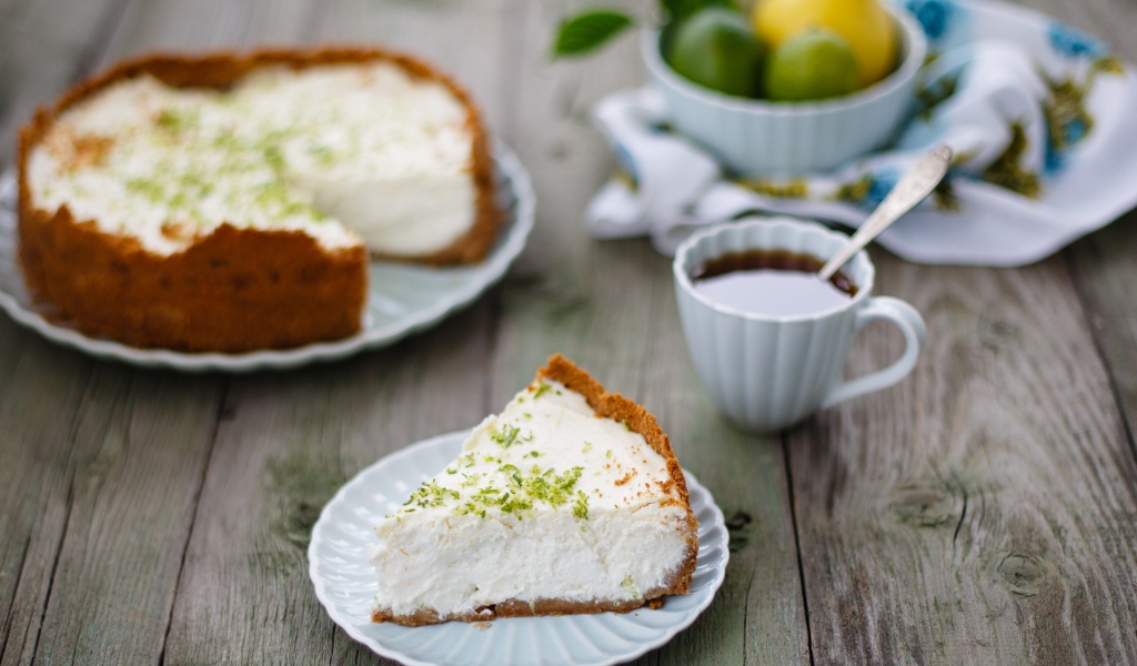 Кусок чизкейка на столе с чашкой чая