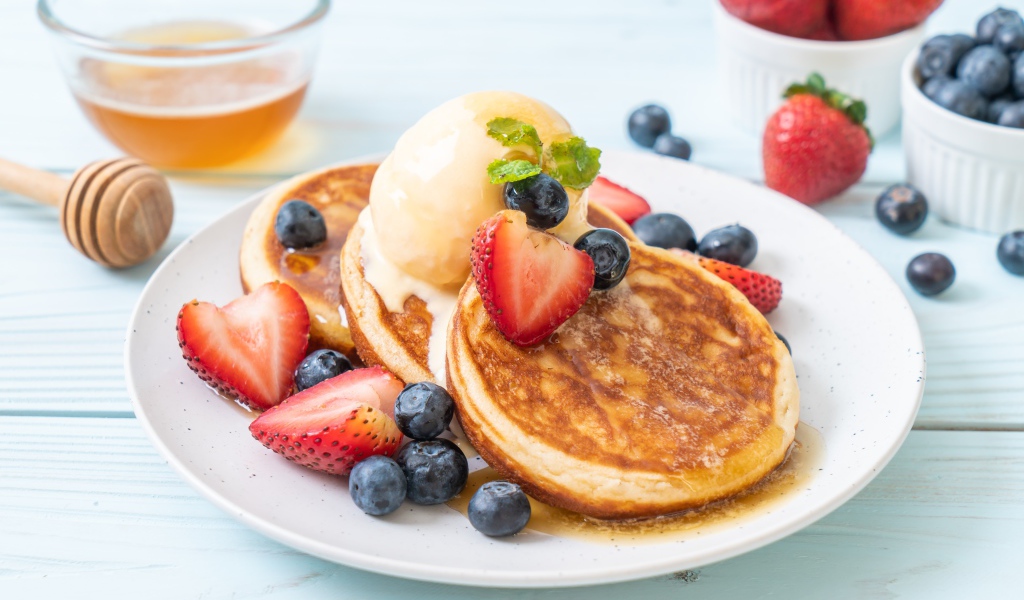 Аппетитные оладьи с мороженым, медом и ягодами клубники и черники