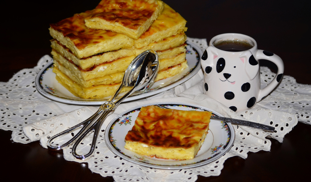 Аппетитный сладкий пирог с чашкой чая на столе