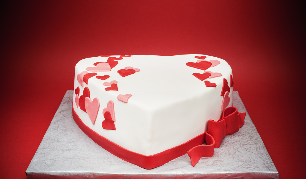 Красивый торт в форме сердца на красном фоне