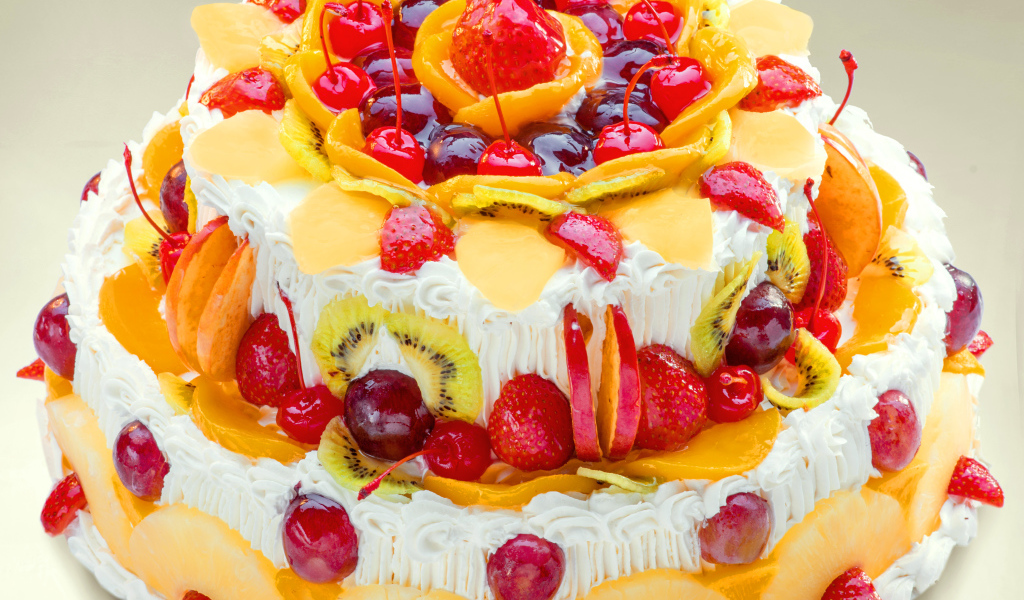 Красиво украшенный ягодами и фруктами торт с кремом