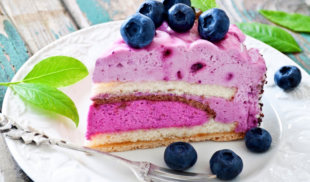 Торт с черничным муссом и свежими ягодами черники на белой тарелке 