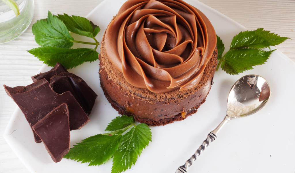 Пирожное с шоколадной кремовой розой на тарелке