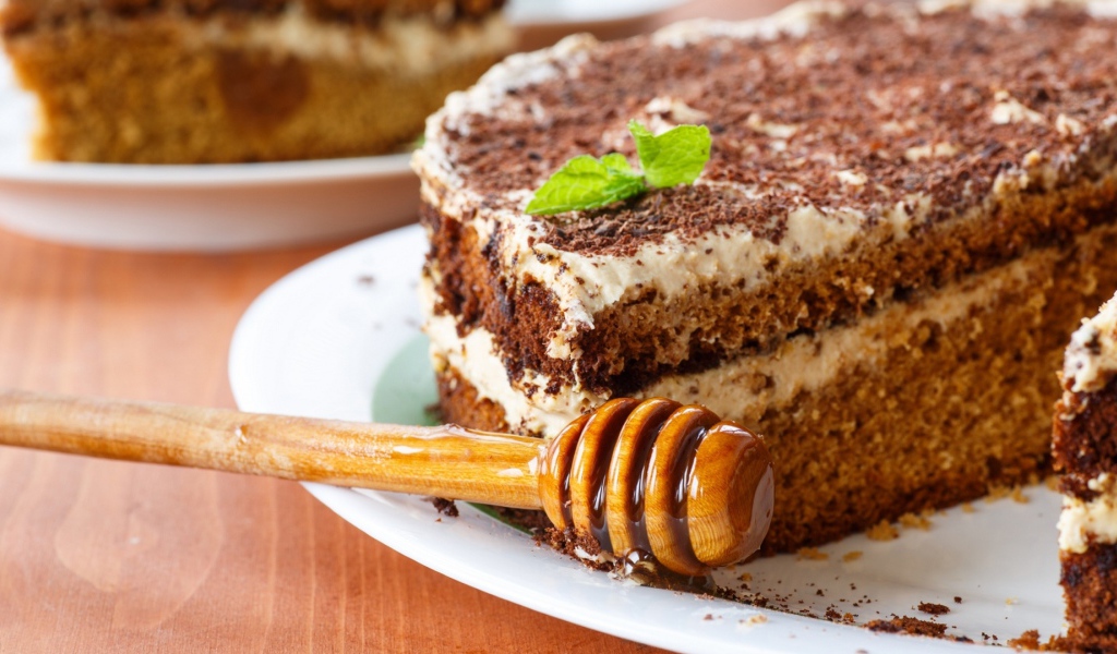 Торт с кремом и шоколадом на тарелке с ложкой для меда