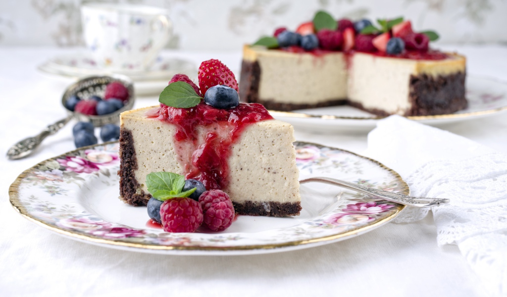 Чизкейк на столе с ягодами малины, черники и клубники