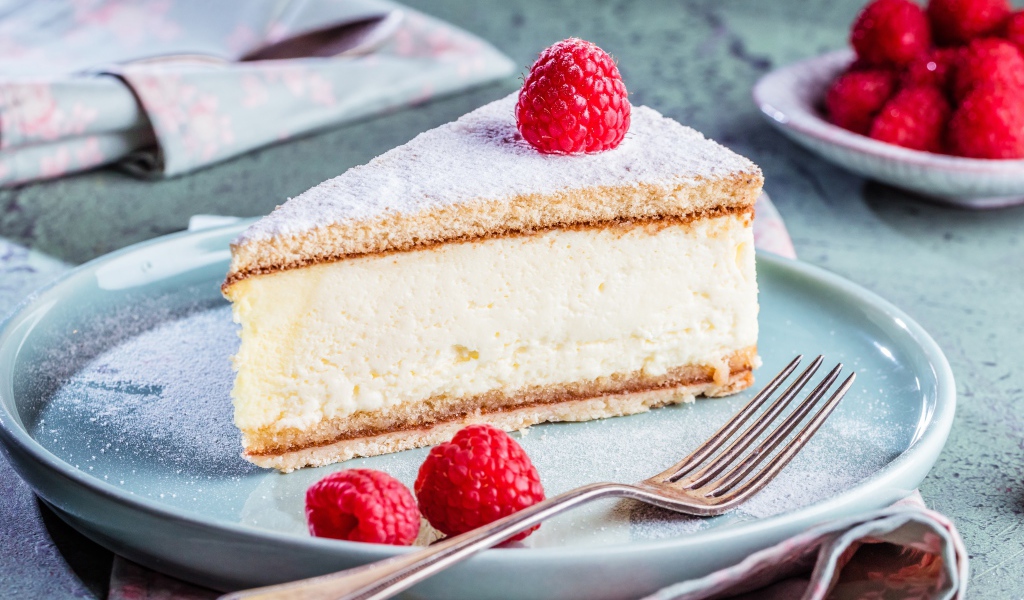 Чизкейк с сахарной пудрой и ягодами малины на тарелке