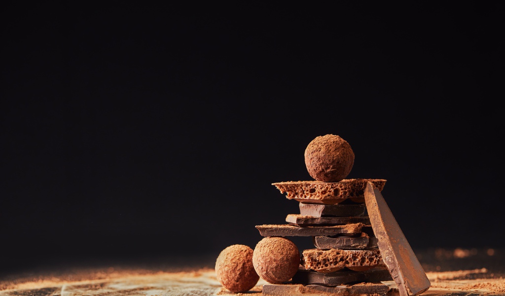 Шоколадные шарики и кусочки шоколада на черном фоне