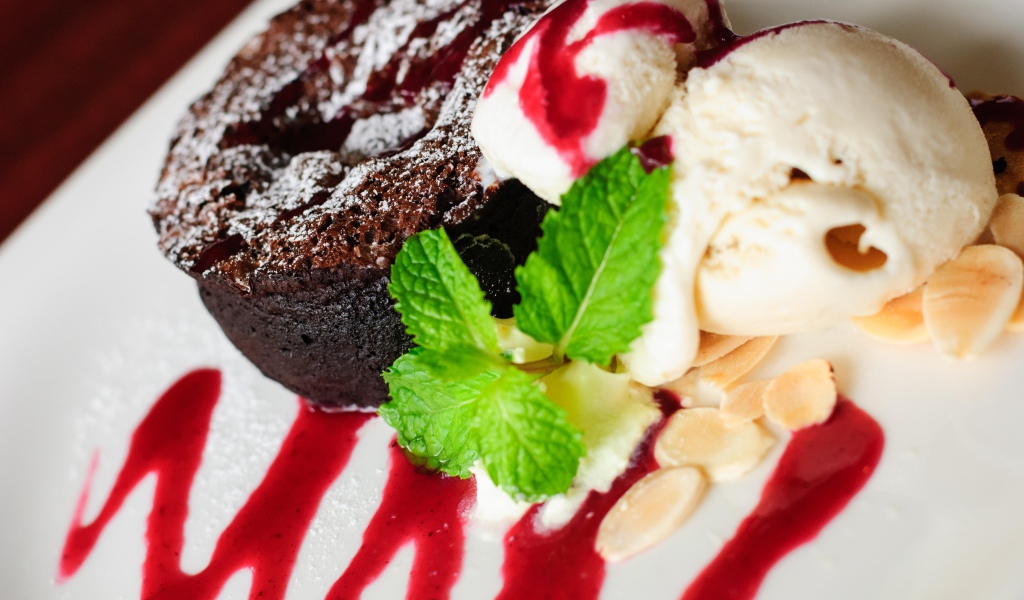Шоколадное пирожное с мороженым и джемом на тарелке