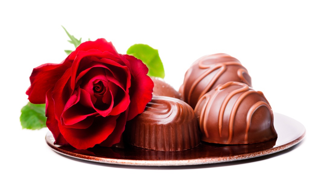Шоколадные конфеты на тарелке с красной розой на белом фоне