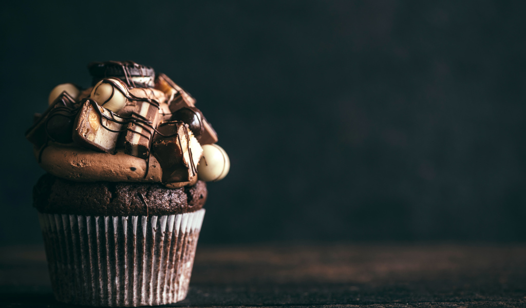 Шоколадный кекс с кремом и конфетами на сером фоне