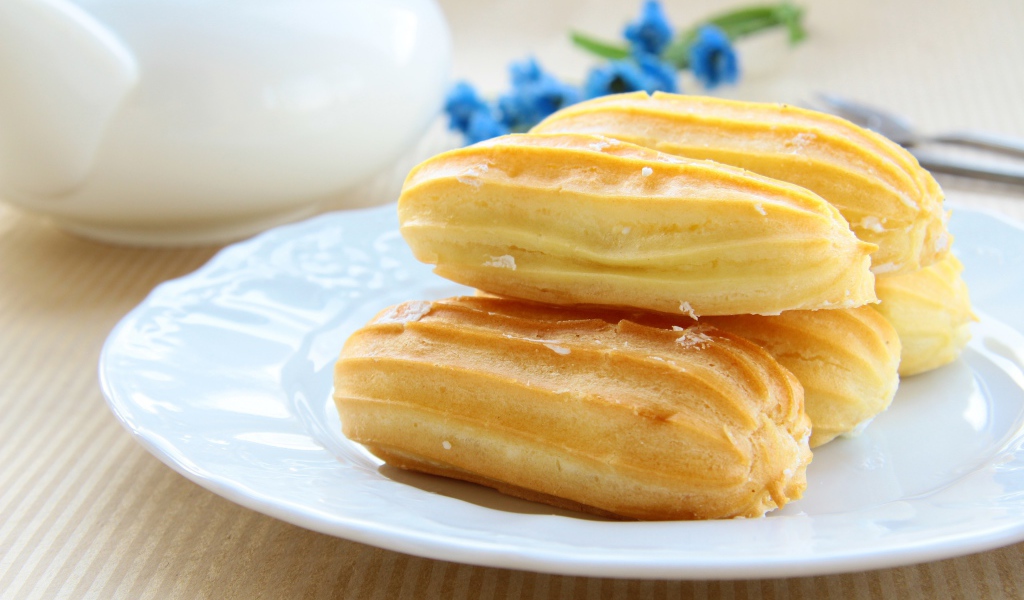 Заварные пирожные на большой белой тарелке 