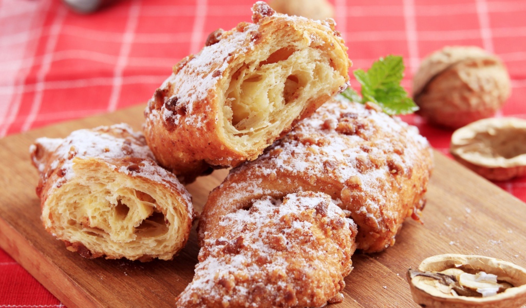Круассаны с орехом и сахарной пудрой на разделочной доске